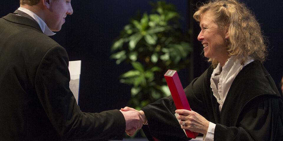 Bouwkundedecaan Elphi Nelissen (rechts) overhandigt het alumnigeschenk aan Tom Steegh. Foto | Vincent van den Hoogen