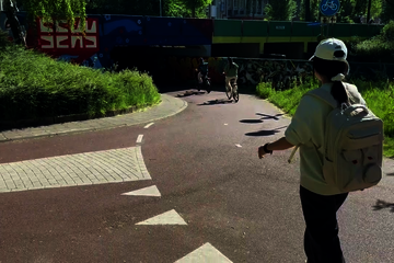 Cyclists and moped riders move crisscross through each other, often at high speeds. Some have to brake, others ring their bells.